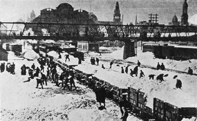 Men shovel snow into train cars to be taken out of the city.