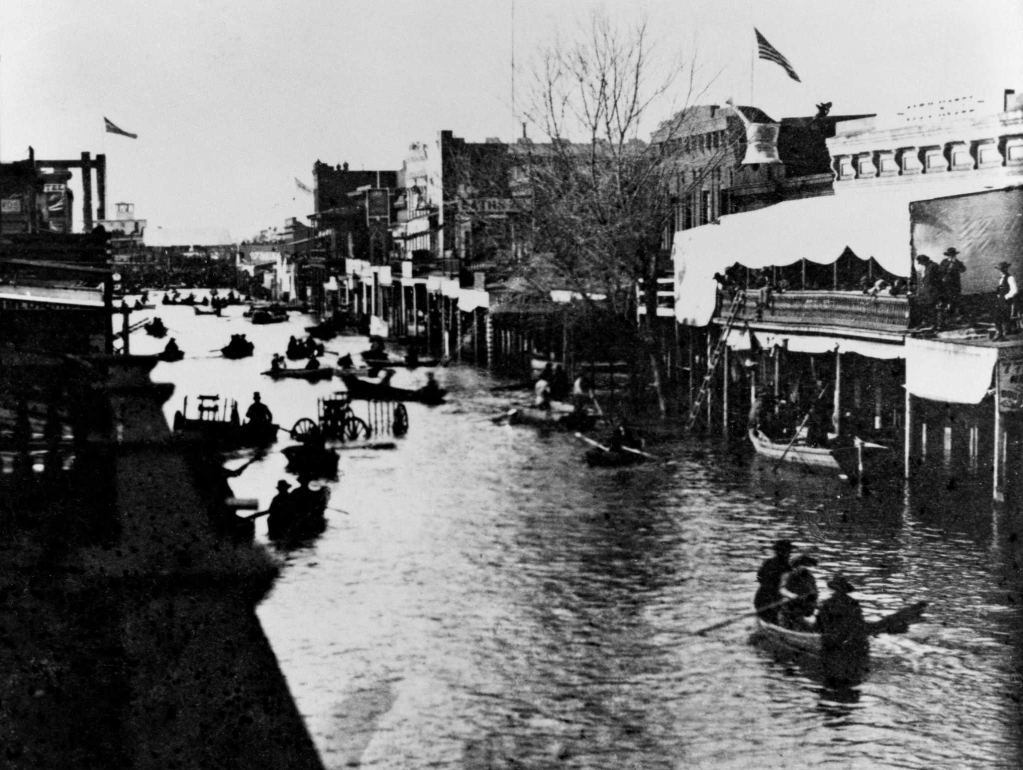 People use rowboats to navigate a flooded Sacramento street.