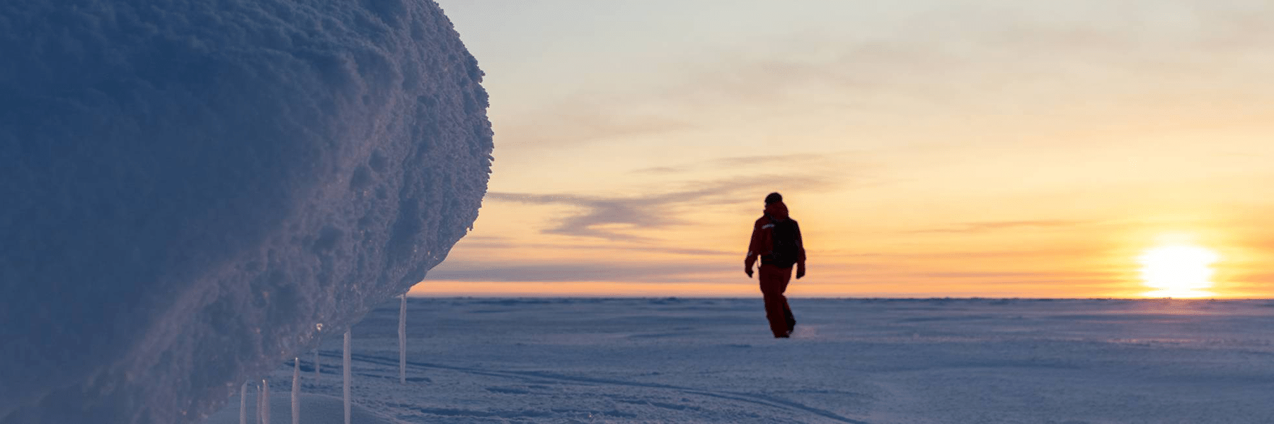 Man walking across frozen landscape