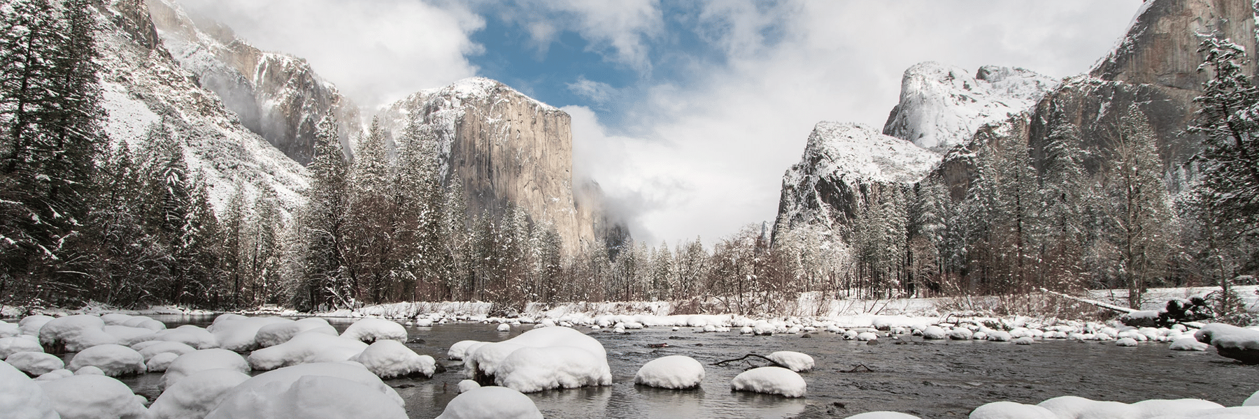 Snow-covered mountains and rocks alongside a body of water