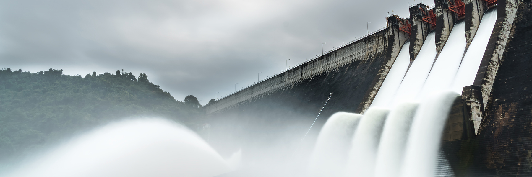 A dam releases a massive amount of water as storm clouds loom. Credit: Adobe Stock