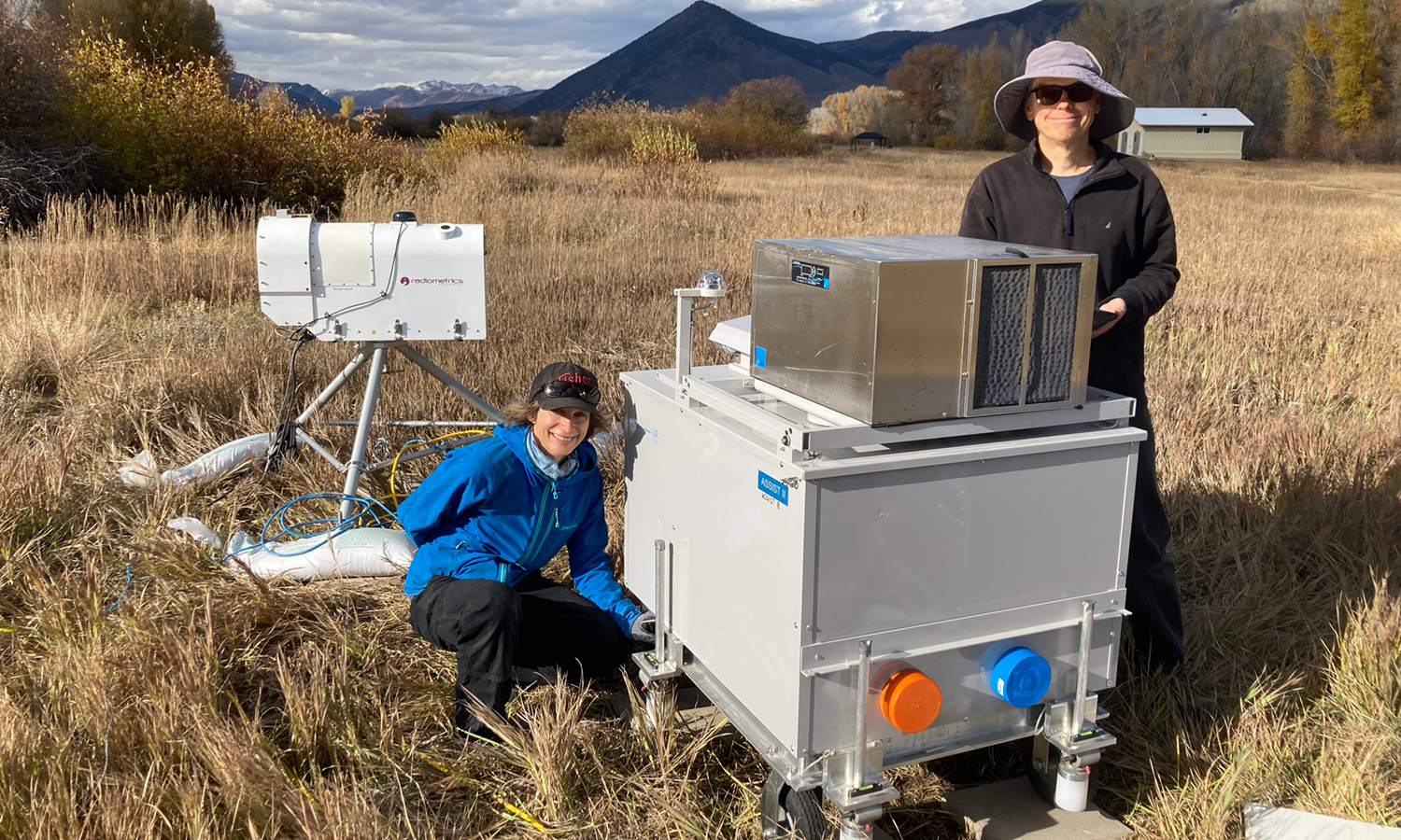 Two researchers install a microwave radiometer and ASSIST instrument at Roaring Judy field site