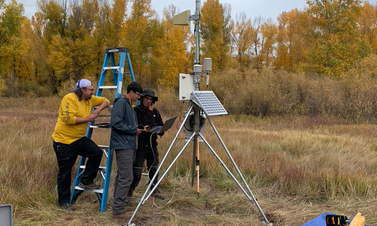 Three engineers setting up a surface met tower.